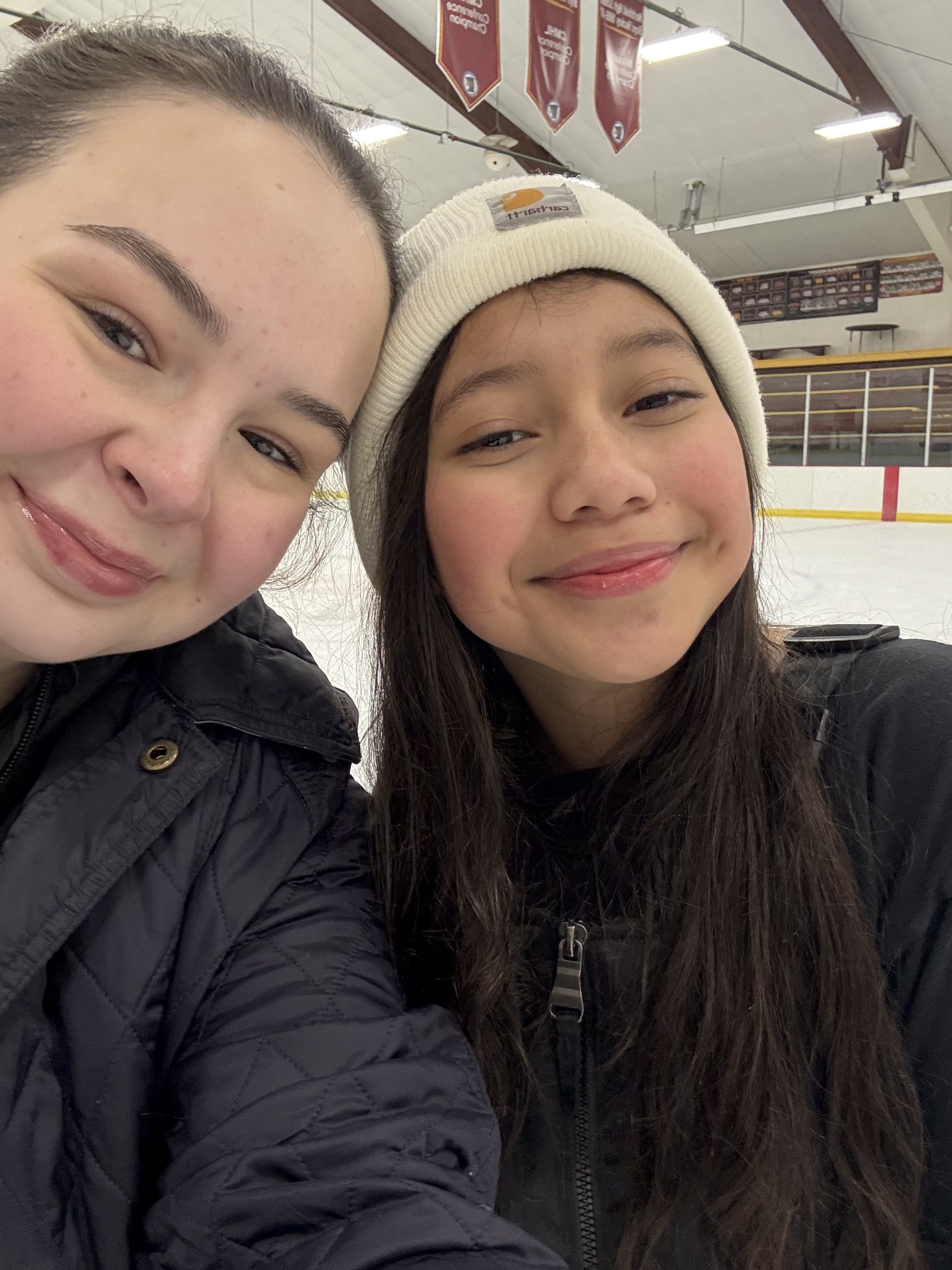 close-up of two girls smiling looking at the camera at a hockey rink