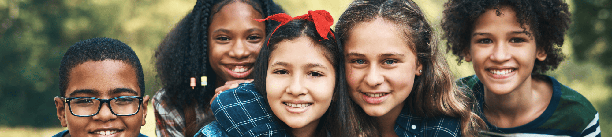 close-up of 5 kids huddled together smiling brightly